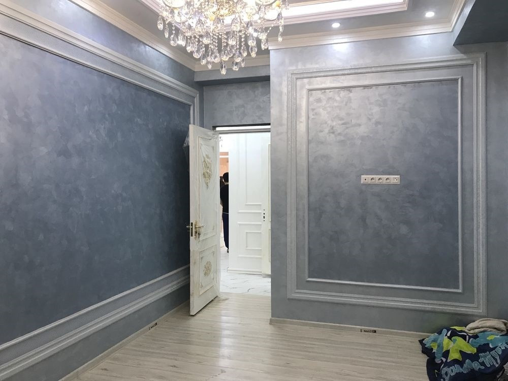 Ремонт процесінде төбеге бояу жағынып жатқан адам