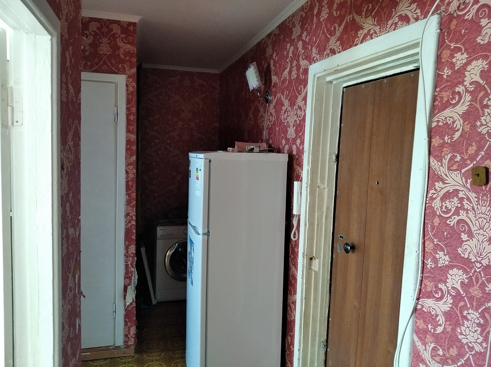 Коридор тоңазытқышпен және кіре беріс есігімен, қабырғалардағы түрлі-түсті қағаздар.