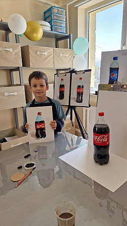 ребенок с рисунком и бутылкой Coca-Cola на столе