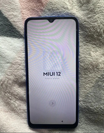 MIUI 12 жүктеліп жатқанын көрсететін экранмен смартфон