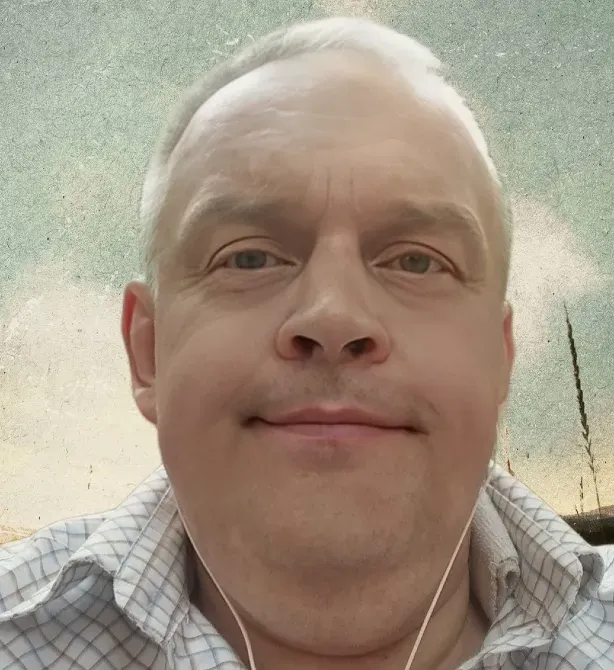 Человек в ярко-оранжевой футболке с надписью #TeamCincinnati, стоящий в помещении с простым интерьером