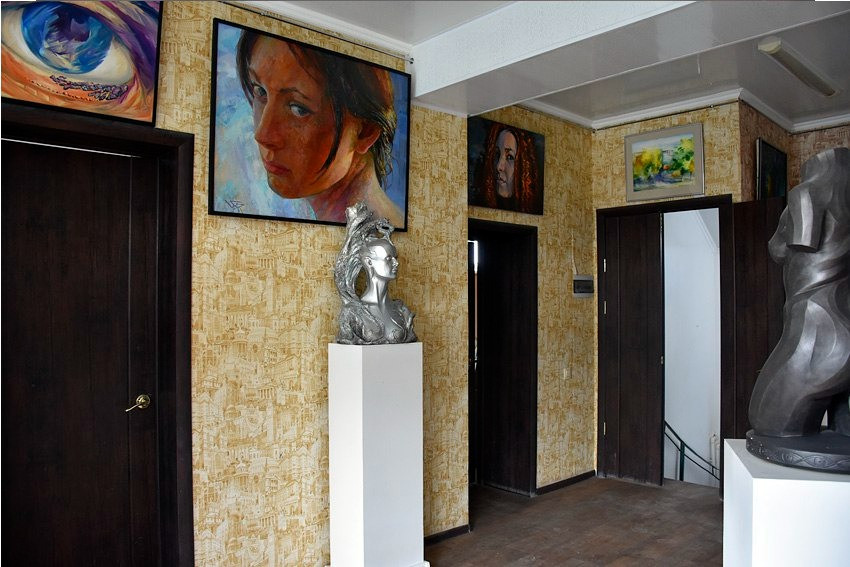 Галерея с произведениями искусства на стенах и скульптурами в выставочных стойках