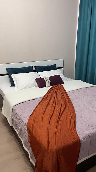 Уголок спальни с акцентным пледом на кровати и подушками