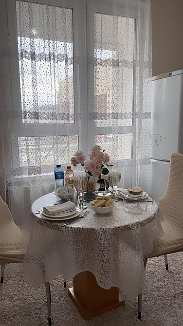 Стол с обедом, украшенный цветами, на фоне окон с шторами