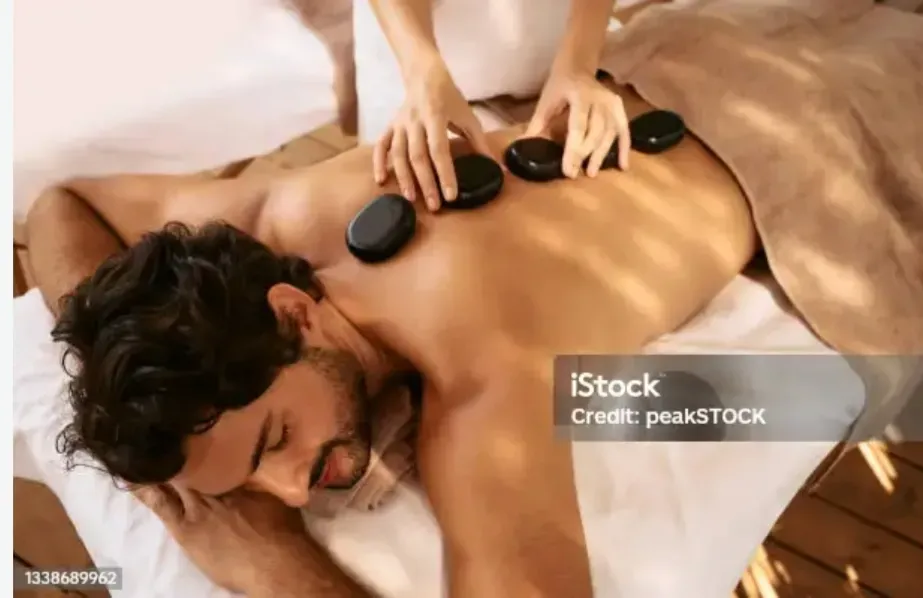 Массажист проводит расслабляющий массаж спины мужчине на массажном столе