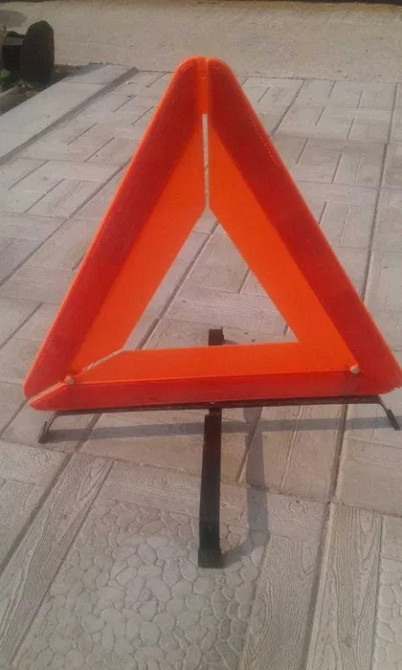 Аварийный треугольник, установленный на земле для предупреждения о ДТП