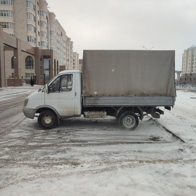 Белый грузовик с тентом припаркован на заснеженной улице