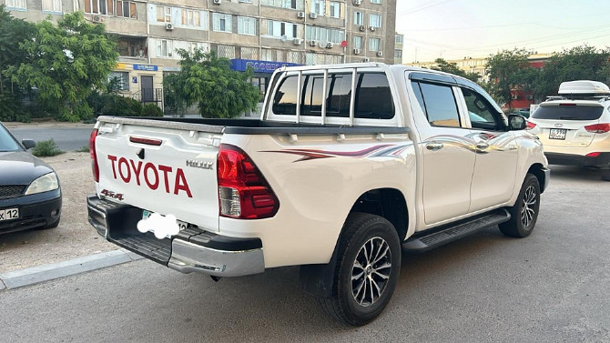 Задний вид белого Toyota с логотипом на кузове