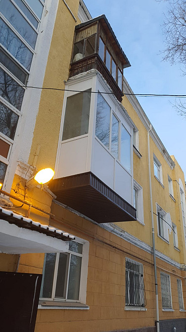 Здание с выделяющимся балконом и светлой жёлтой окраской