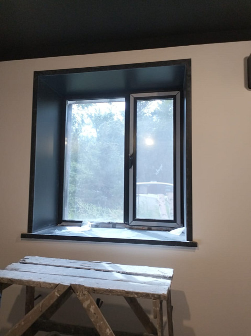 Окно с черной рамой и подоконником в комнате с лесным видом
