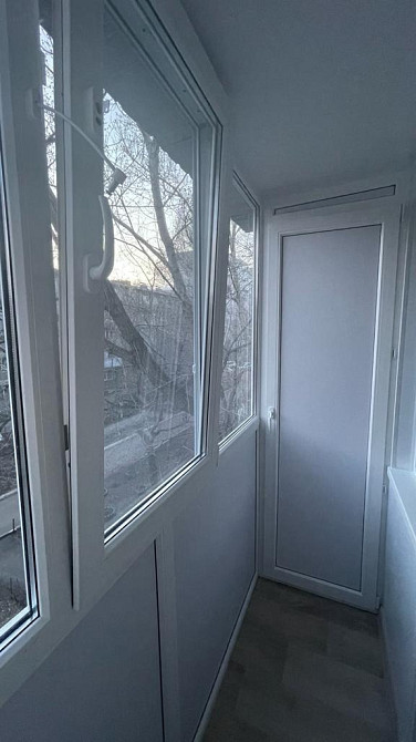 Балкон с белыми стенами и большими окнами, вид на улицу