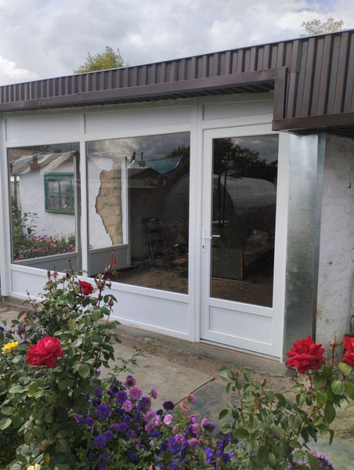 Стеклянный фасад дома с цветами и садом на фоне, открытое пространство с выходом на улицу