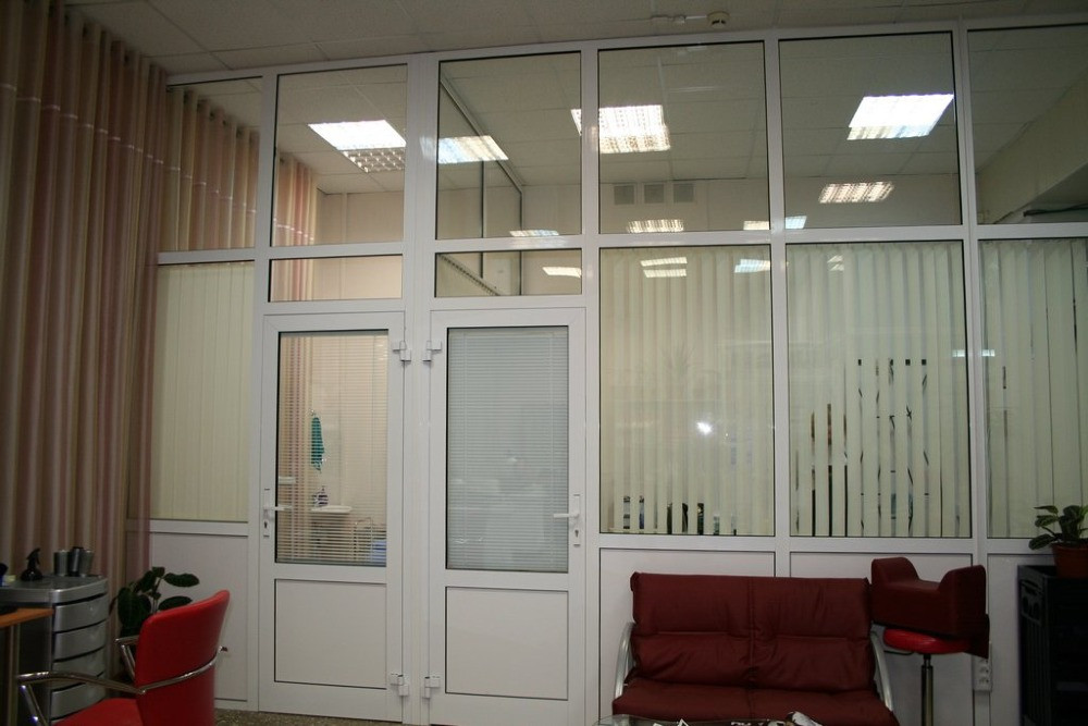 Офисное помещение с стеклянной стеной и дверью, оформленное в светлых тонах