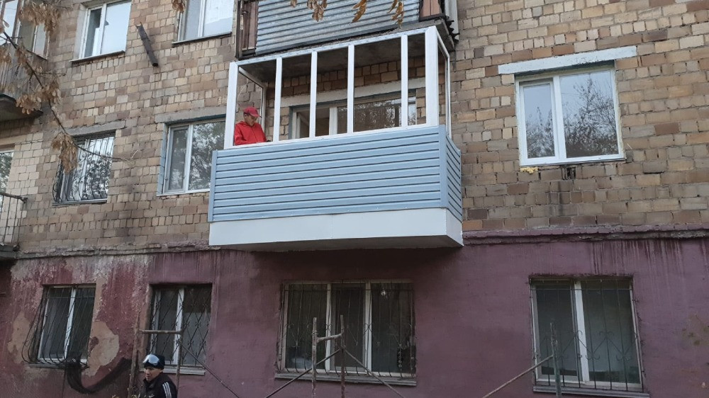 Ақ панельдері және түрлі-түсті төбесі бар балкон, үстінде адам тұр