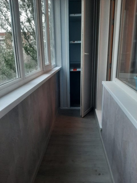 Уютный балкон с окнами и деревянным полом, на стенах обои