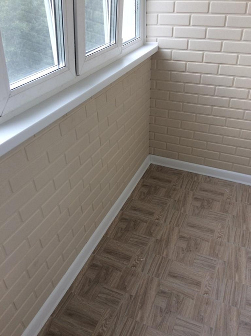 Угловой балкон с белыми стенами и деревянным полом, солнечное освещение