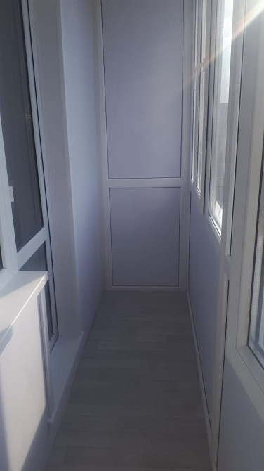 Просторный интерьер балкона с панорамными окнами и светлыми стенами