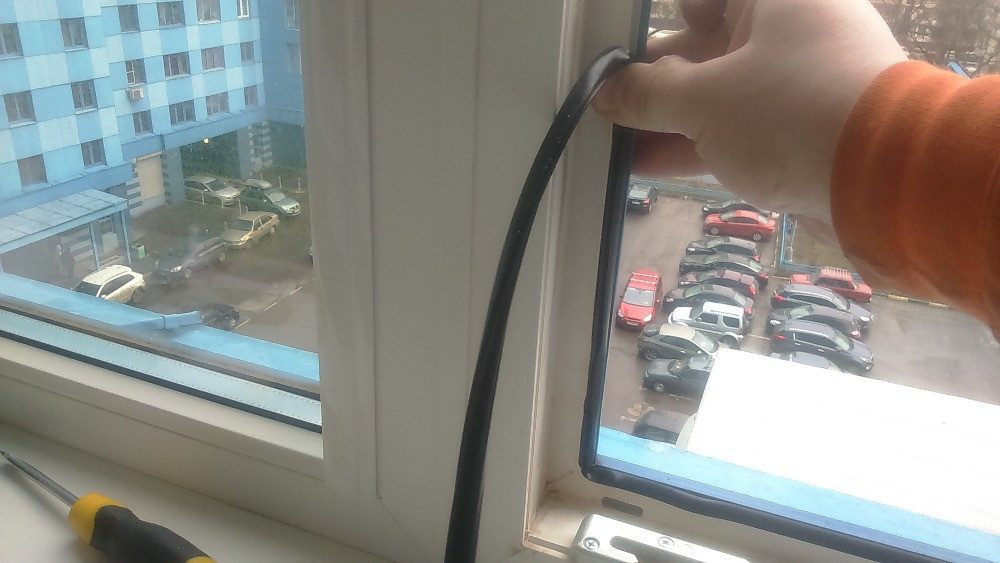 Процесс установки оконного уплотнителя с видом на улицу