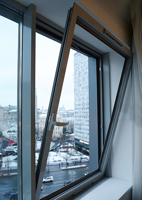 Открытое окно с видом на город в зимний день, снежный пейзаж