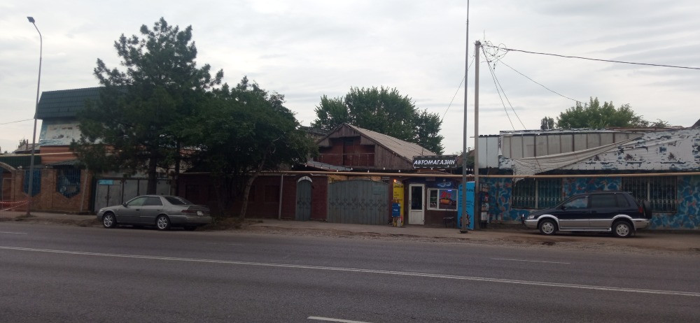 Улица с двумя припаркованными автомобилями рядом с автосервисом
