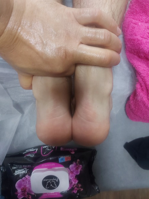 Процесс массажа: руки массажиста на стопах клиента