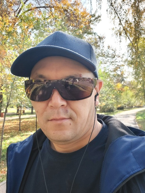 Человек в кепке и солнцезащитных очках на прогулке в парке