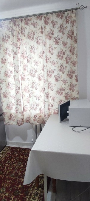 Комната с окнами, занавесками в цветочный узор и столом с принтером