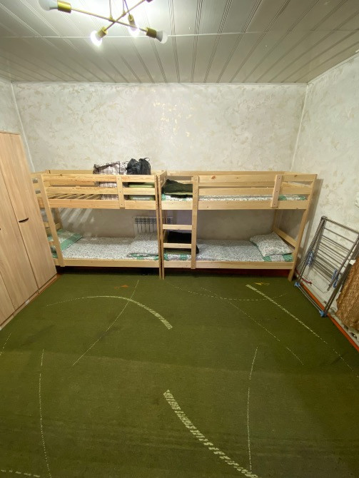 Внешний вид комнаты с двухъярусными кроватями и зеленым ковром
