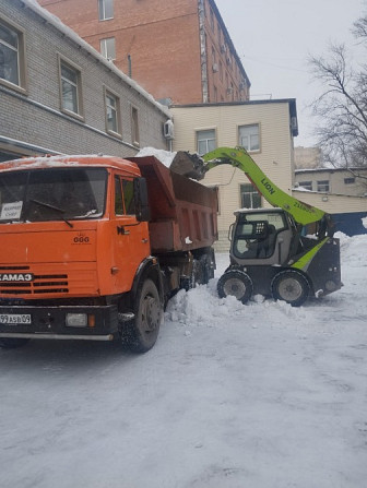 Грузовик КАМАЗ с подъемником, убирающим снег во дворе