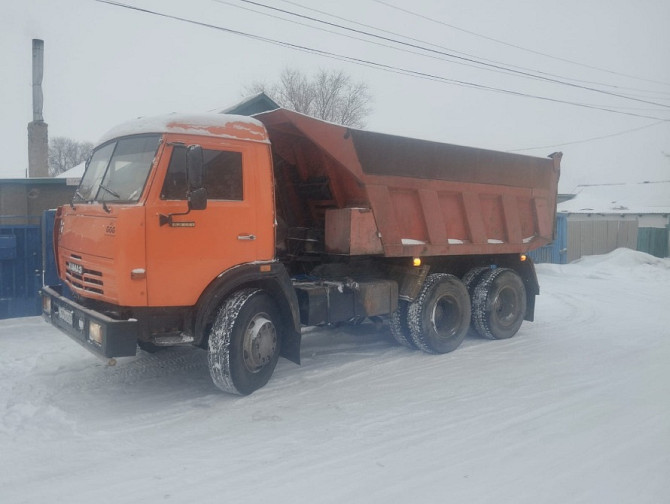 Грузовик КАМАЗ с открытым кузовом на снежной стоянке