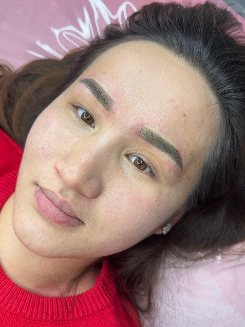 Қызыл свитердегі қыз, кушеткеде, жарқын көзқараспен және ұқыпты макияжбен.