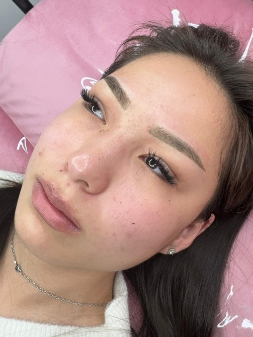 Ұзын шашты қыз, ақ свитерде, кушеткеде, көздерінде макияжбен