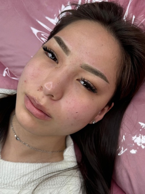 Ұзын шашты қыз, ақ свитерде, кушеткеде жатып, босаңсып көрінеді