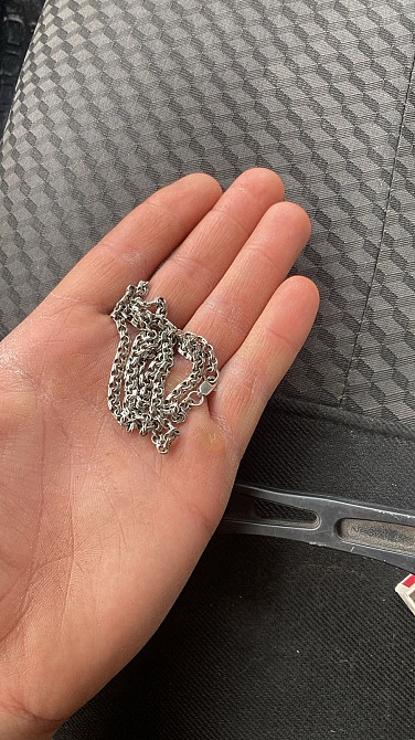 Показан человек, держащий в руке цепочку из серебра