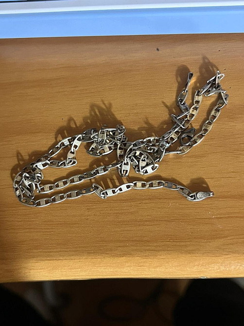 Цепочка из металла, разложенная на деревянной поверхности