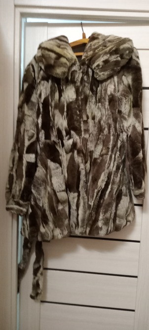 Пальто из меха с капюшоном, висящее на вешалке