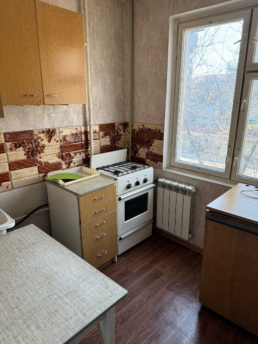 Кухня с плитой и оконным светом, сантехникой и кухонной мебелью