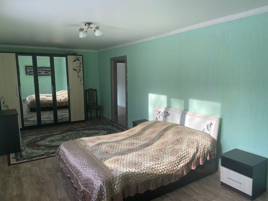 Спальня с большой кроватью, зеркальным шкафом и светло-зелеными стенами