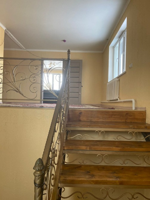 Лестница с деревянными ступенями и коваными перилами, освещенная естественным светом