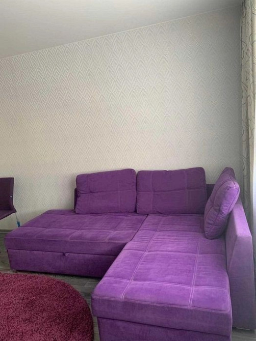 Уголок с фиолетовым диваном и круглым ковром