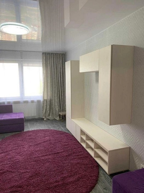 Просторная гостиная с мебелью и фиолетовым ковром