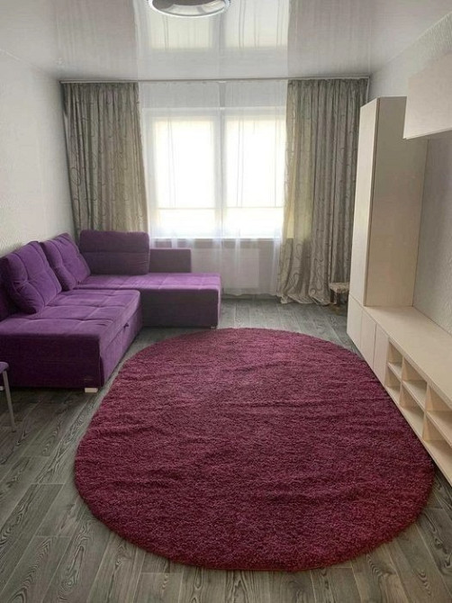 Гостиная с фиолетовым угловым диваном и большим окном