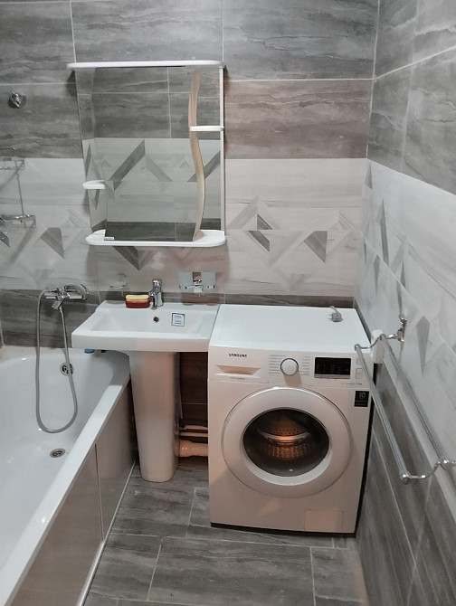 Ванная комната с функциональным расположением стиральной машины и ванной