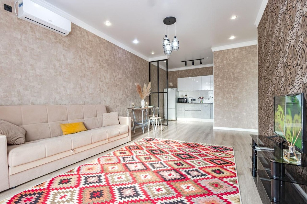 Гостиная с диваном, столом и кухней на фоне