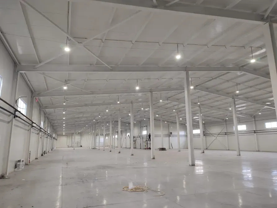 Құрылыс үстінде жатқан өндірістік ғимараттар, аспан фонында сұр және қызыл элементтерімен.