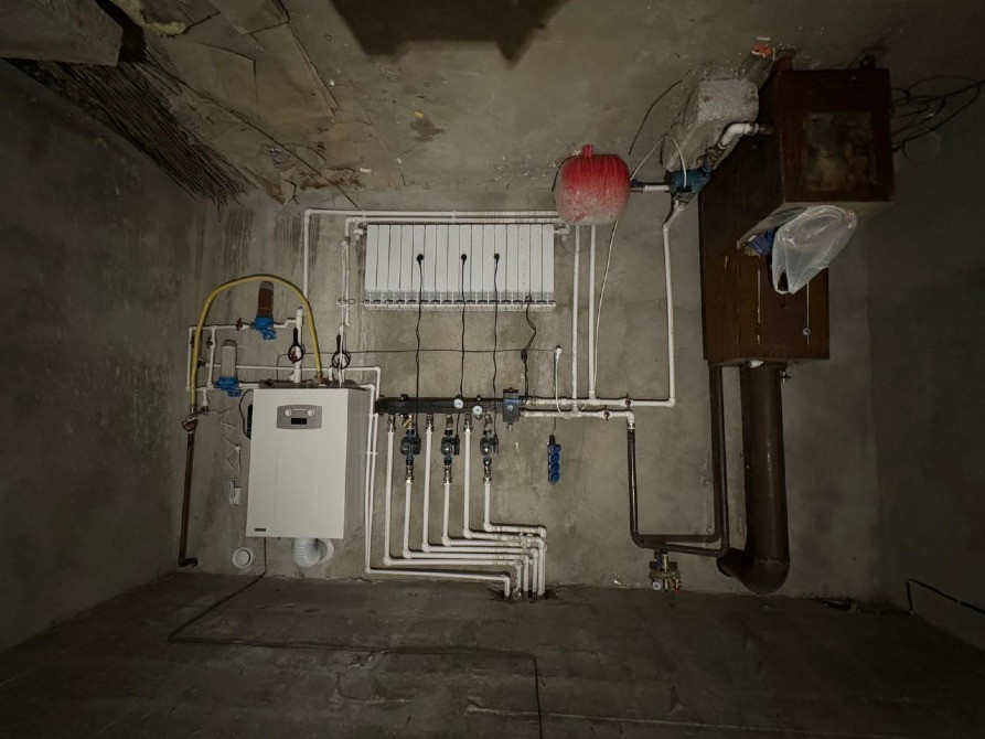 Система отопления в подвале с трубами и радиатором
