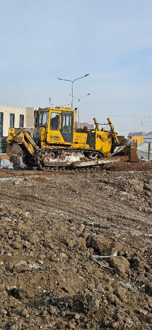 Желтый бульдозер на строительной площадке, работающий на земле