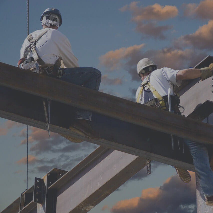 Құрылысшылар құрылыс алаңында биік жерде болат балка орнатуда