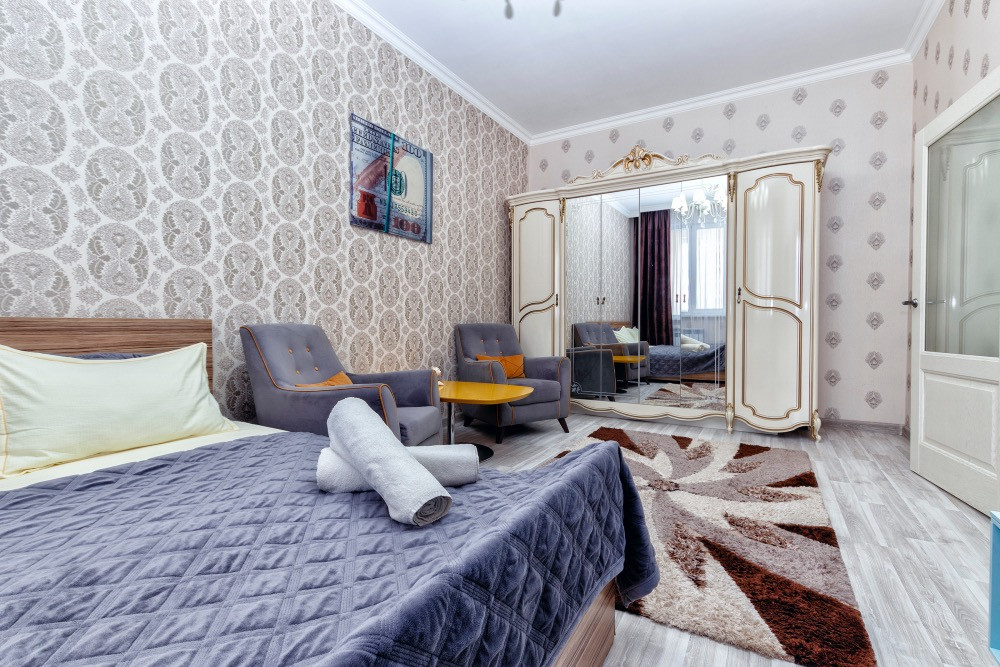 Светлая спальня с зеркальным шкафом и комфортной мебелью