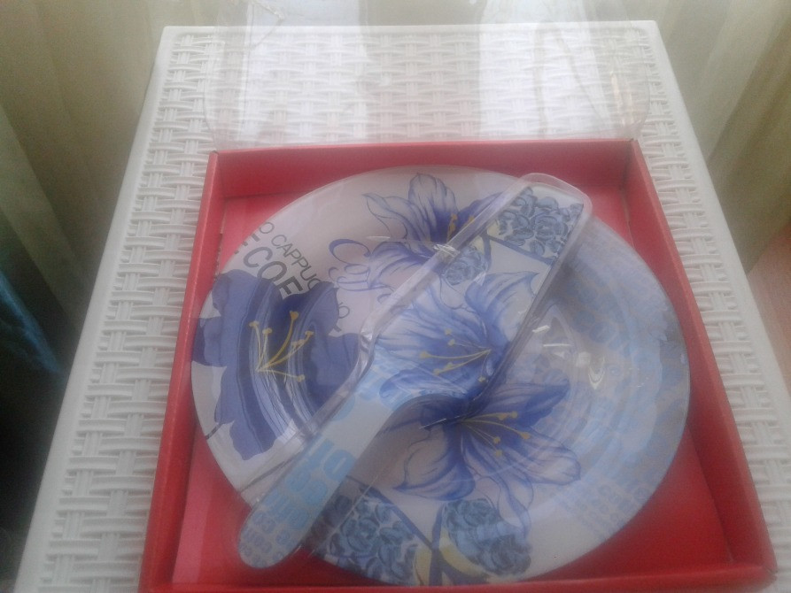 Набор посуды с цветочным узором на тарелках и ножом, представлен на красной подставке